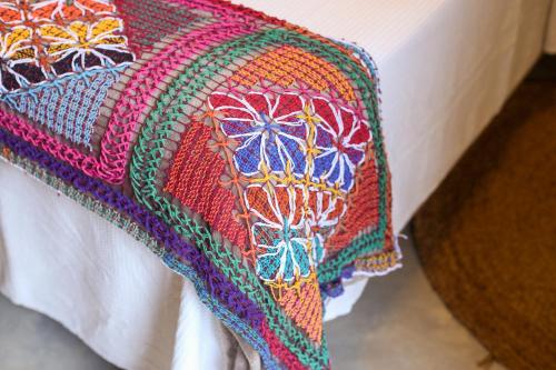 a bed with a colorful blanket on it at NORI POUSADA in São Miguel dos Milagres
