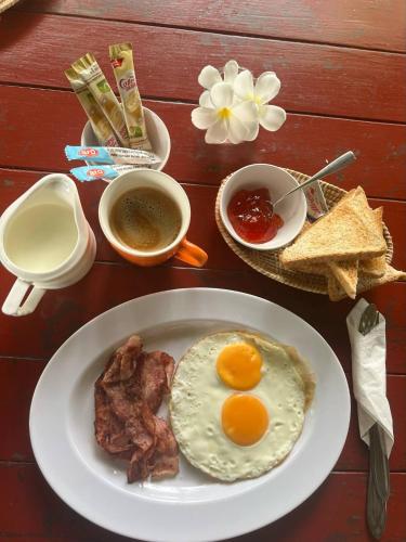 Un plato de desayuno con huevos, tocino y tostadas. en Tropical Paradise Leelawadee Resort, en Ko Chang