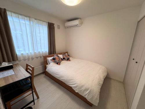 a bedroom with a bed and a desk and a window at Nomad Stay Chitose in Chitose