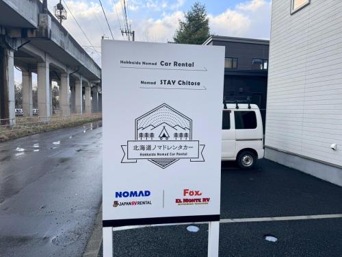 a sign in a parking lot next to a building at Nomad Stay Chitose in Chitose