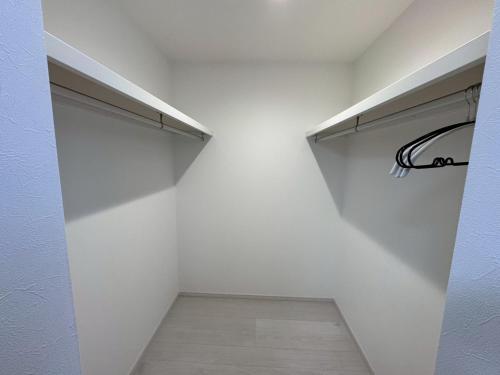 a walk in closet with a white wall at Nomad Stay Chitose in Chitose