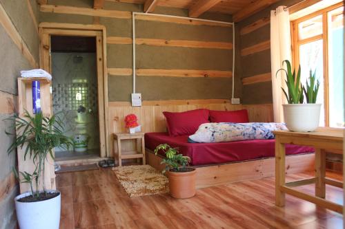 a room with a red bed in a wooden room at Mysterious Kutla Cottage,Kutla, Tosh in Chhorang
