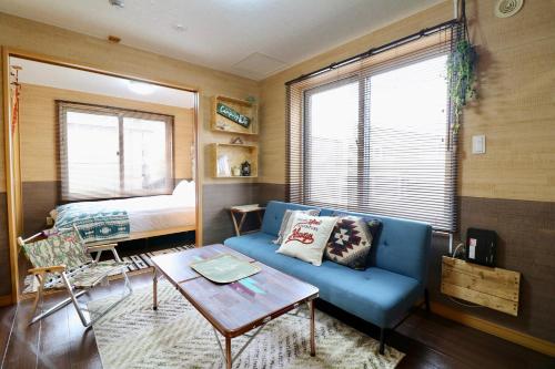 a living room with a blue couch and a bed at Jeunesse Court in Toyohira