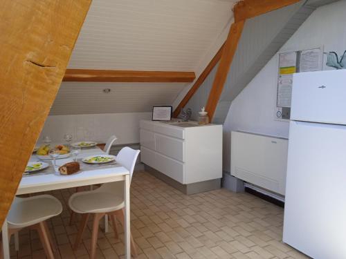 a small kitchen with a table and a refrigerator at Les Roses de Rita in Boisset-lès-Montrond