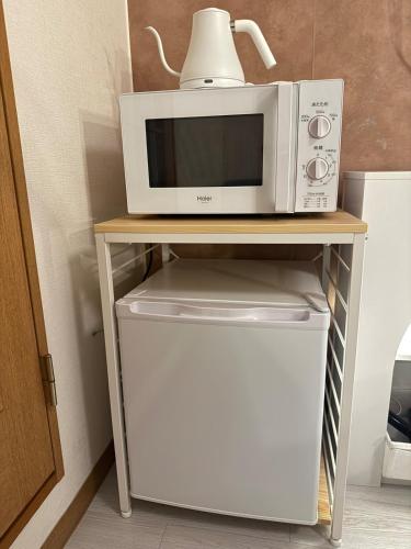 a microwave sitting on top of a table with a refrigerator at Omori 8min Stylish and comfortable room in Tokyo
