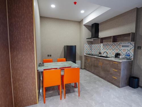a kitchen with orange chairs and a table and a counter at Bojon Hotel Ulaanbaatar - Soyolj Mall in Ulaanbaatar