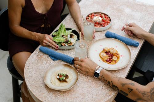 a group of people sitting at a table with food at Boni Beach Lombok Boutique Hotel & Villas in Selong Belanak
