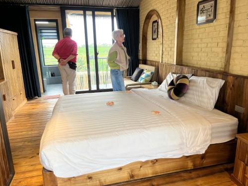two people standing in a bedroom with a large bed at Duong Lam Eco Home in Sơn Tây