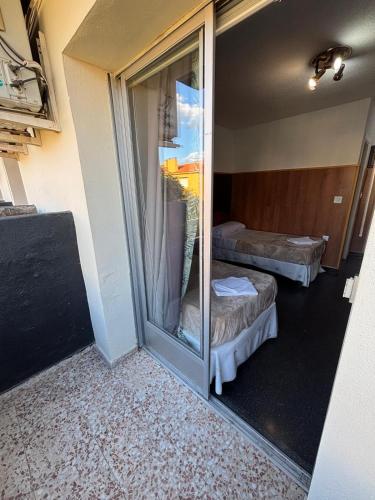 a room with two beds and a glass window at Hotel Don Jose in Puertollano