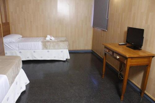 a room with two beds and a desk with a television at Hotel Don Jose in Puertollano