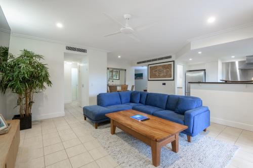 a living room with a blue couch and a table at Mandalay Luxury Beachfront Apartments in Port Douglas
