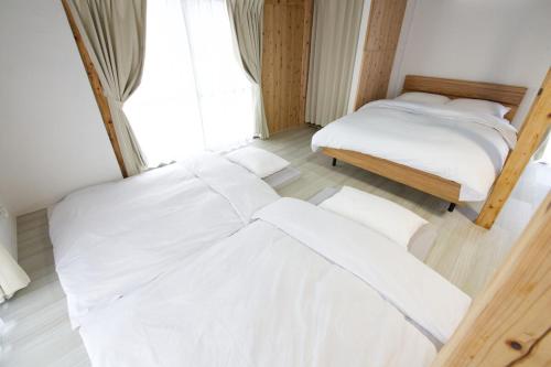 two beds in a room with white sheets at 沖縄古民家 Villa JYANA in Nakijin