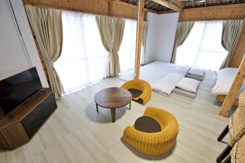 a living room with a tv and a couch and a table at 沖縄古民家 Villa JYANA in Nakijin