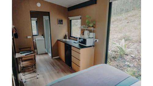 una piccola cucina con lavandino in una casetta di Wilderness View by Tiny Away a Mooloolah