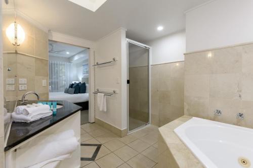 a bathroom with a shower and a sink and a tub at Mandalay Luxury Beachfront Apartments in Port Douglas