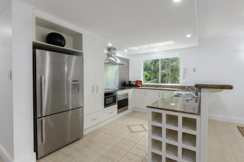 a kitchen with a stainless steel refrigerator and white cabinets at Mandalay Luxury Beachfront Apartments in Port Douglas
