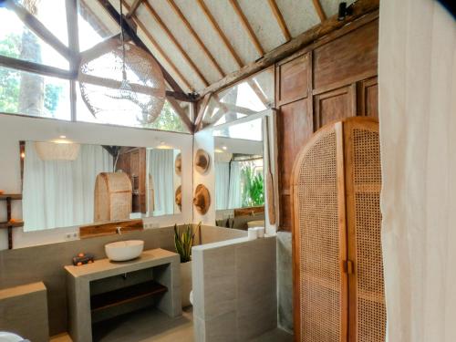 a bathroom with a tub and a sink and a mirror at Musa Bintang Villas and Bungalows Gili Air in Gili Air