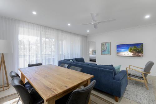 a living room with a wooden table and blue chairs at Mandalay Luxury Beachfront Apartments in Port Douglas