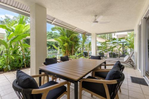 a dining room with a wooden table and chairs at Mandalay Luxury Beachfront Apartments in Port Douglas