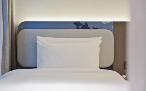 a bed with a white pillow and a blue headboard at Atour Light Hotel Shenzhen Nanshan Nanyou Clothing City in Shenzhen