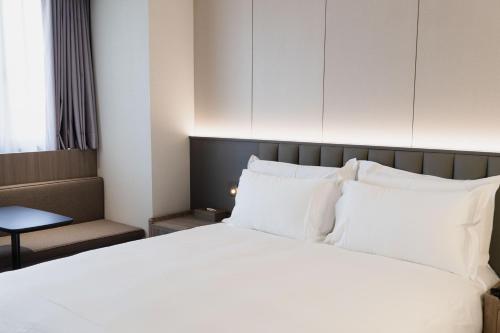 a bedroom with a large white bed with white pillows at Talmud Hotel Classic Taiwan Boulevard in Taichung