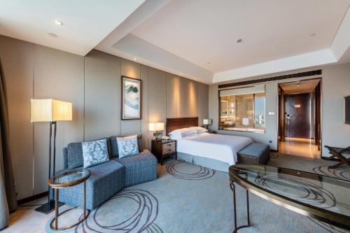 a hotel room with a bed and a couch at Yancheng Jinying Shangmei Hotel in Yancheng