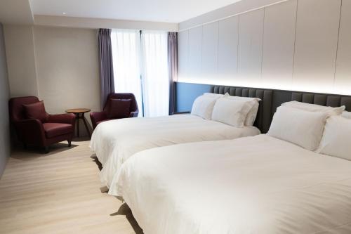 a hotel room with two beds and a chair at Talmud Hotel Classic Taiwan Boulevard in Taichung