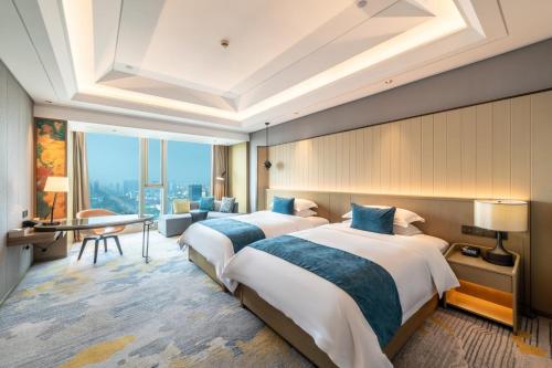 a hotel room with two beds and a desk at Yancheng Jinying Shangmei Hotel in Yancheng