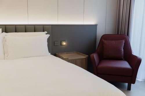 a hotel room with a bed and a chair at Talmud Hotel Classic Taiwan Boulevard in Taichung