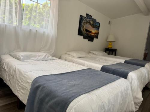 two beds in a room with white walls and a window at Los Angeles Hideaway - Villa Costanso in Los Angeles