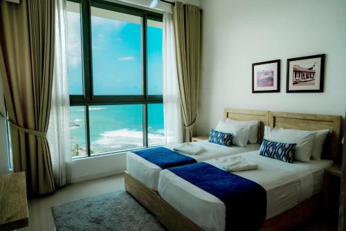 two beds in a room with a large window at Oceanfront Galle by ICC in Galle