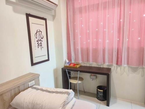 a bedroom with a bed and a desk and a pink curtain at 一個人背包客棧 in Wujie