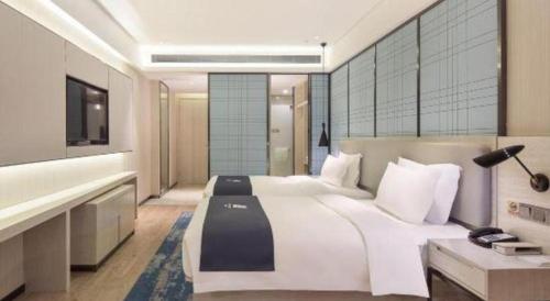 a bedroom with a large white bed and a television at Echarm Hotel Changsha High-speed Railway Station in Changsha