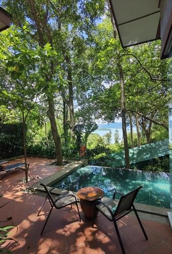 a patio with chairs and a table and a swimming pool at Ambong Pool Villas - Private Pool in Pantai Cenang