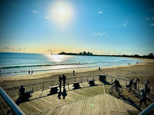 a group of people walking on the beach at Barooga1- Mooloolaba Canal Front Apartment in Mooloolaba