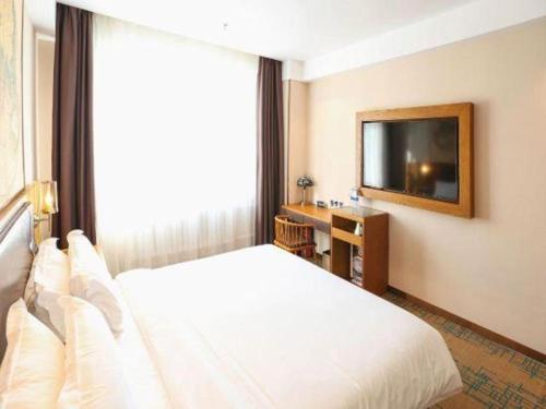 a bedroom with a white bed and a large window at James Joyce Coffetel Changchun People's Square in Changchun