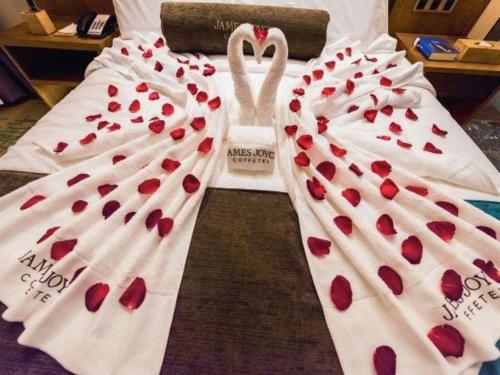 two wedding gowns covered in red hearts on a bed at James Joyce Coffetel Changchun People's Square in Changchun