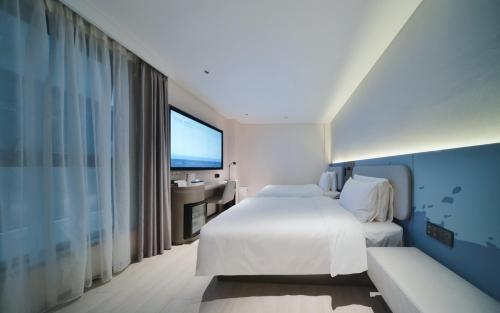 a bedroom with a white bed and a large window at Atour Light Hotel Shenzhen Nanshan Nanyou Clothing City in Shenzhen