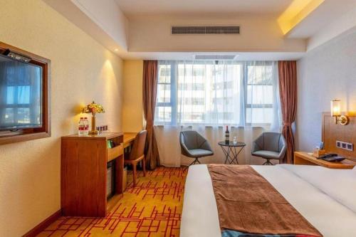 a hotel room with a bed and a desk and a window at James Joyce Coffetel Kunming Railway Station Huancheng Nan Road Metro Station in Kunming