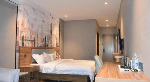 a bedroom with a bed and a table and a painting at Shell Hotel Kaifeng Jin'an Road Bianxihu Wanda Plaza in Kaifeng