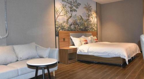 a bedroom with a bed next to a couch at Shell Hotel Kaifeng Jin'an Road Bianxihu Wanda Plaza in Kaifeng