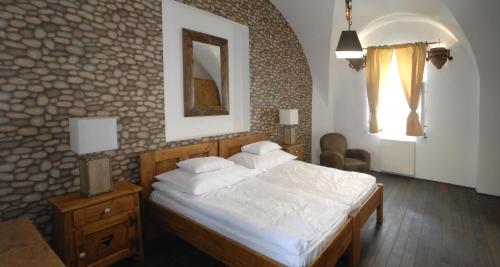 a bedroom with a bed and a stone wall at Régi Posta Hotel és Étterem in Debrecen