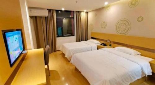 a hotel room with two beds and a flat screen tv at GreenTree Inn Linhai Jiangnan Avenue Express in Linhai