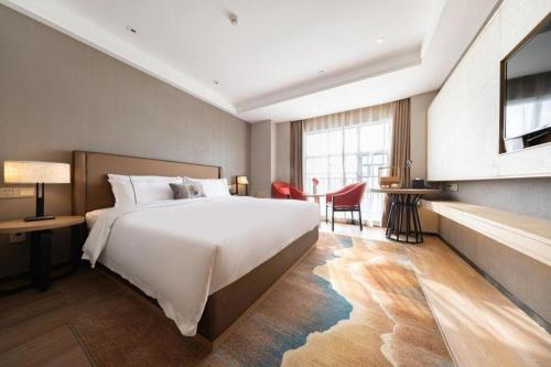 a bedroom with a large white bed and a table at E-Cheng Hotel Xiaogan Hanchuan Renming Road in Xiaogan