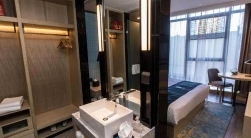 a bathroom with a sink and a bed in a room at Echarm Hotel Hefei West Qilitang Metro Station in Hefei