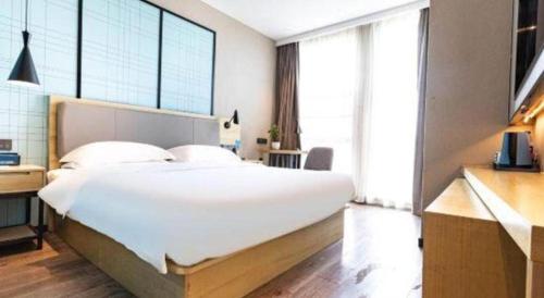 a bedroom with a large white bed and large windows at Echarm Hotel Hefei West Qilitang Metro Station in Hefei