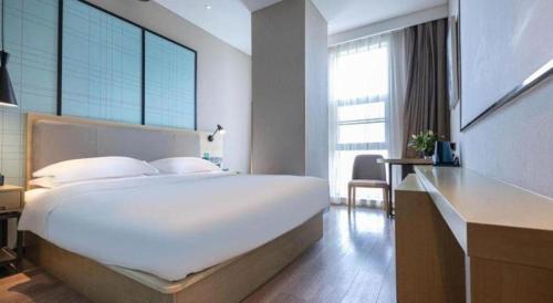 a bedroom with a large white bed and a desk at Echarm Hotel Hefei West Qilitang Metro Station in Hefei