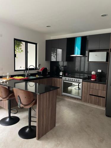 a kitchen with black cabinets and a black counter top at Habitación y baño privado en lujoso residencial con alberca climatizada in Santa Gertrudis