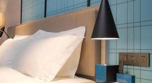 a bed with a white pillow and a black lamp at Echarm Hotel Hefei West Qilitang Metro Station in Hefei