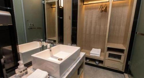 a bathroom with a sink and a tub and a toilet and a sink at Echarm Hotel Hefei West Qilitang Metro Station in Hefei